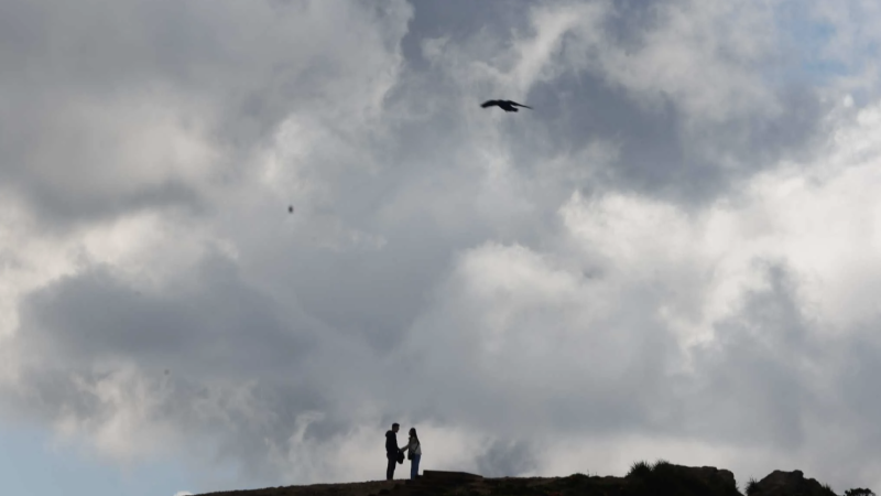 A couple are silhouetted under a cloudy peak as they hike at San Francisco’s Twin Peaks in March. Temperatures were below normal in California in 2023, thanks to an especially cold and wet winter. Lea Suzuki. The Chronicle 2023