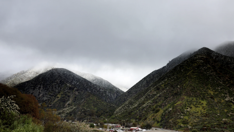 A helicopter flies above the foothills of the San Gabriel Mountains with a dusting of snow in the Angeles National Forest in Los Angeles County