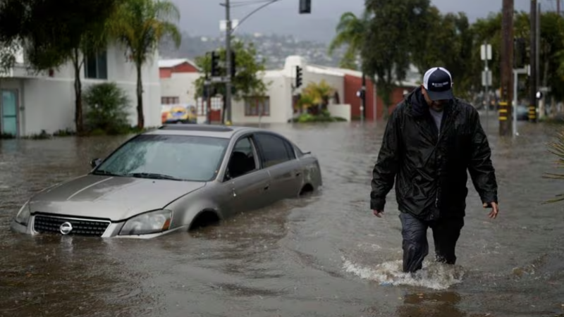 A man walks past a submerged vehicle on a flooded street- Thursday- Dec - - in Santa Barbara- Calif Jae C Hong : AP